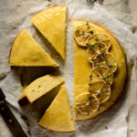 Lemon cake on parchment paper with have cut into slices